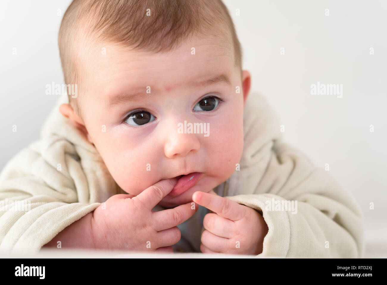 Portrait of an adorable smiling baby biting her own fingers putting her