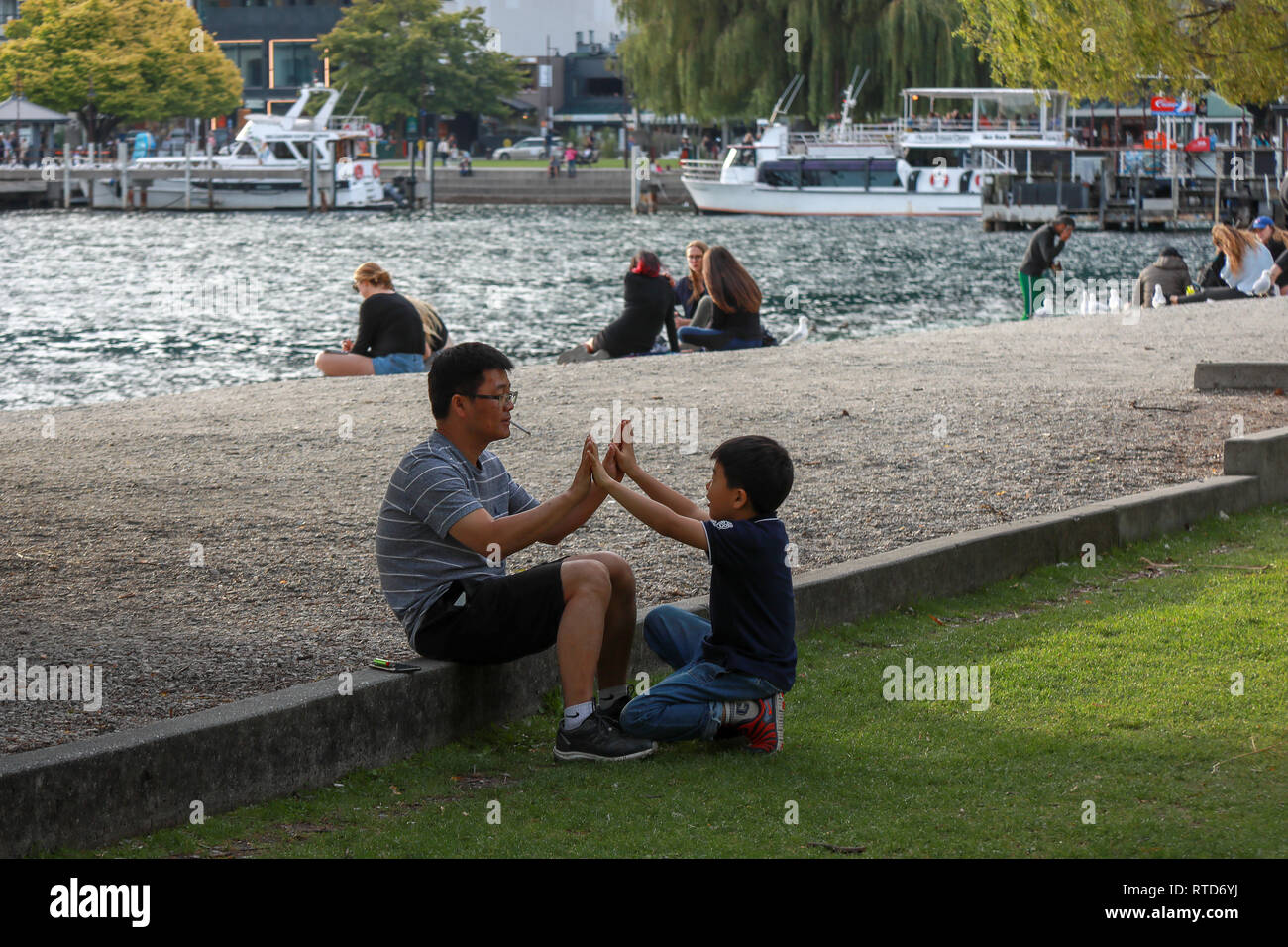 Man and boy playing games on Queenstown beach at sunset by Lake Wakatipu, Queenstown, New Zealand South Island Stock Photo