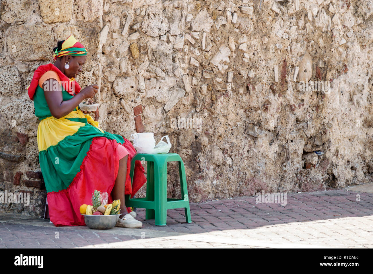 Cartagena Colombia,Black Afro Caribbean Palenquera,fruit vendor,woman female women,eating,sitting,traditional costume,cultural heritage symbol,COL1901 Stock Photo