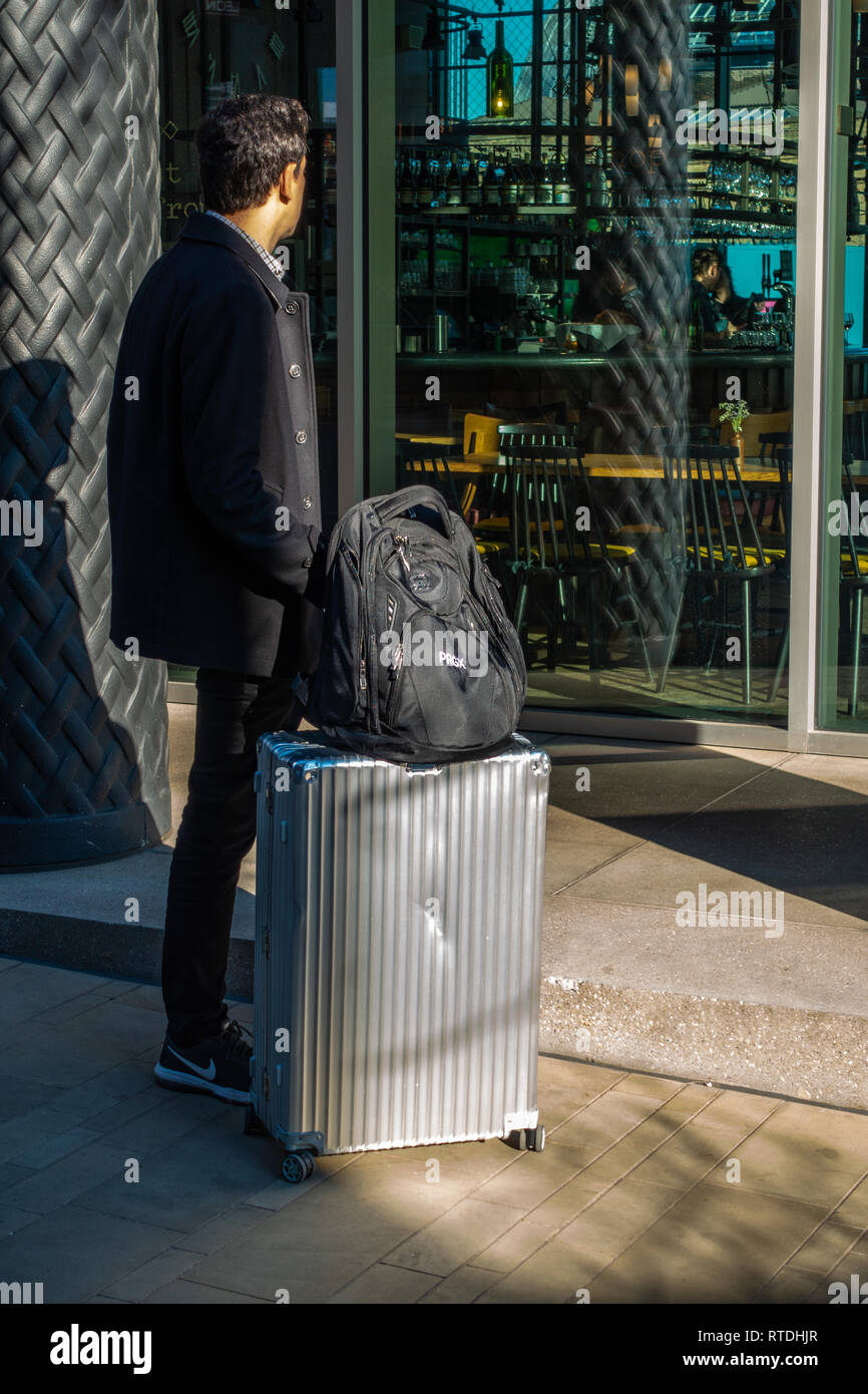 A traveler waits for a train with his Rimowa suitcase on a subway