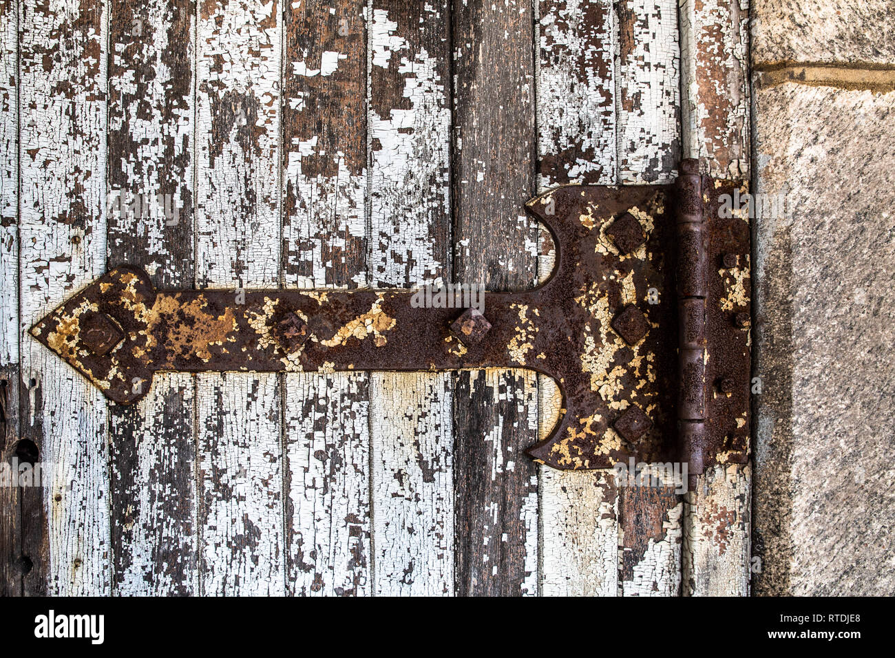 Detailed close-up of rusty old hinge on a door with peeling paint Stock Photo