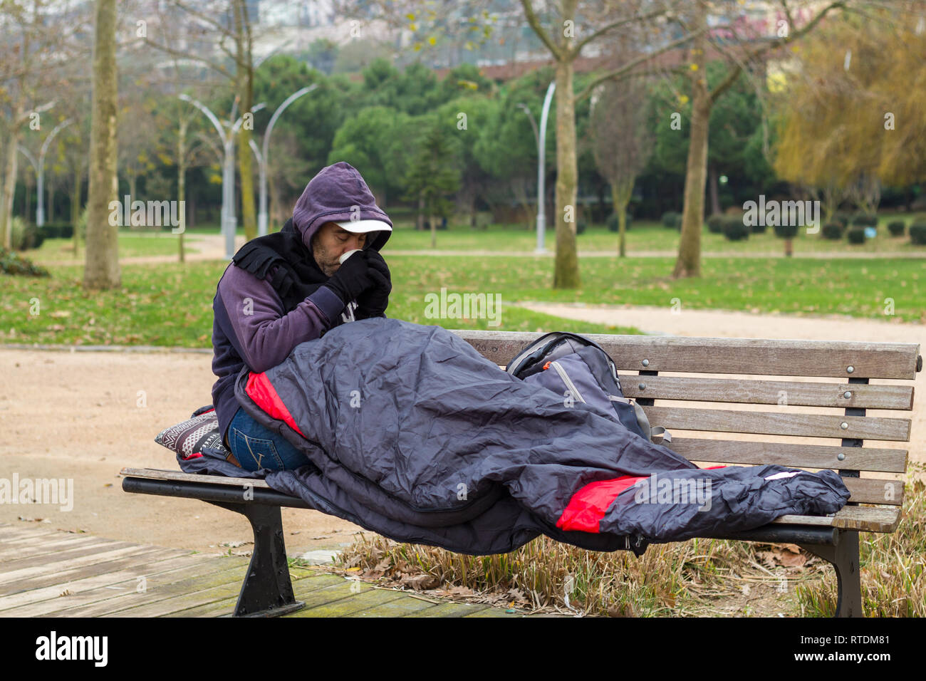 Homeless man is drinking coffee on bench Stock Photo Alamy