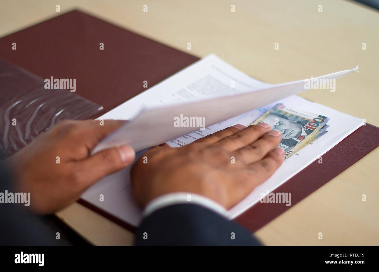 Man accepting bribe under some contract papers, Peruvian soles currency in notes of 100 bills. Bribery and corruption concepts. Stock Photo