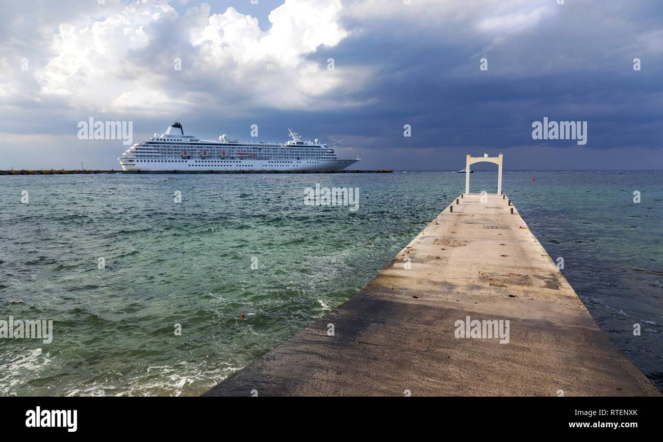 Large Cruise Ship Liner and Stone Pier Water View against the background of dramatic stormy sky in port of Cozumel, Mexico Yucatan Peninsula Stock Photo