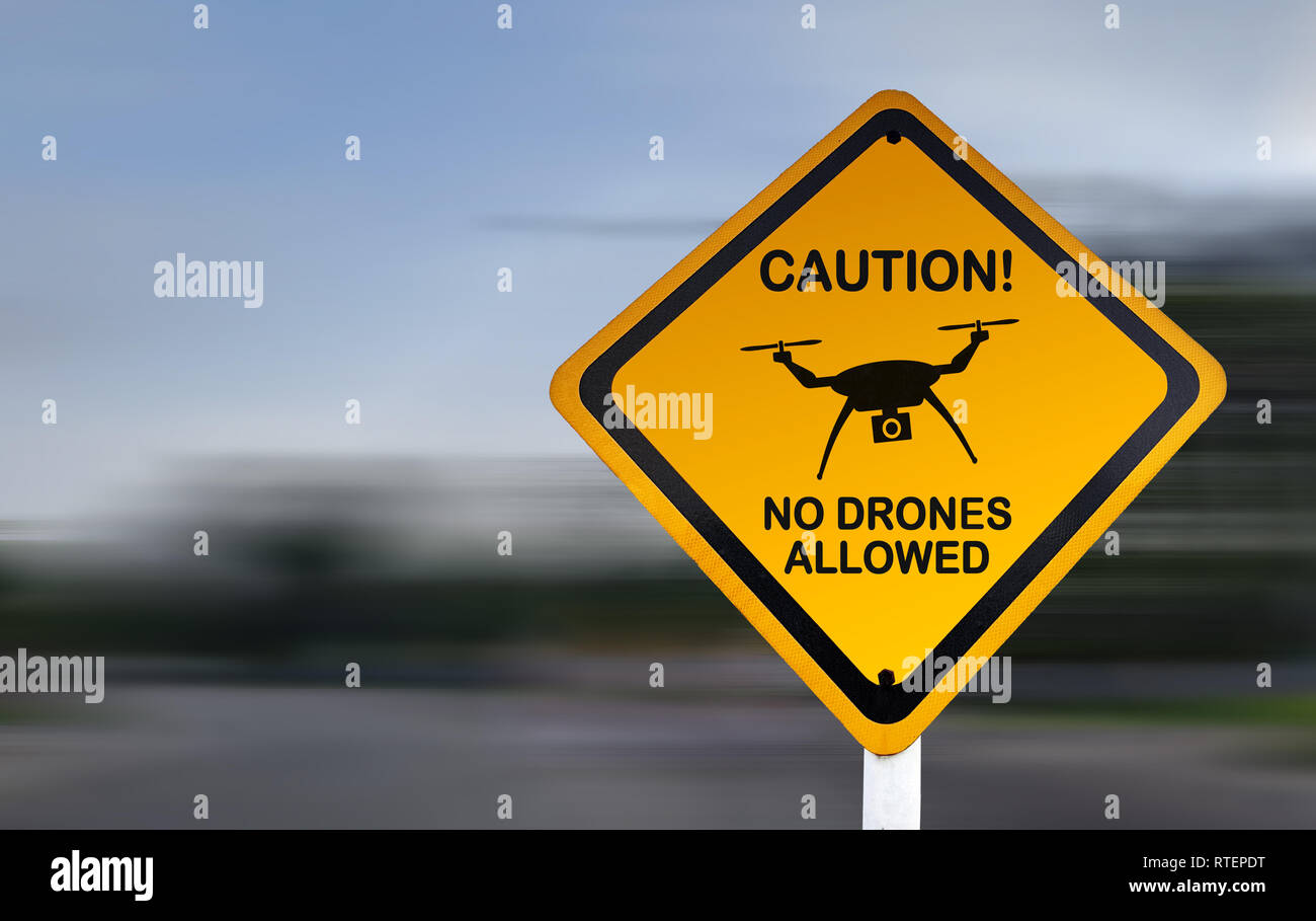 Drone warning sign, no drones allowed. Yellow caution sign with drone icon and blurred speed background. Airspace restriction notice Stock Photo