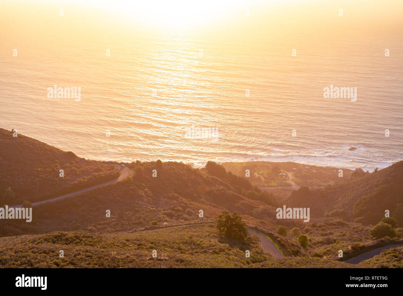 Vista view of the Big Sur coastline high up in the hills overlooking the California coast as the sunsets along the horizon. Stock Photo