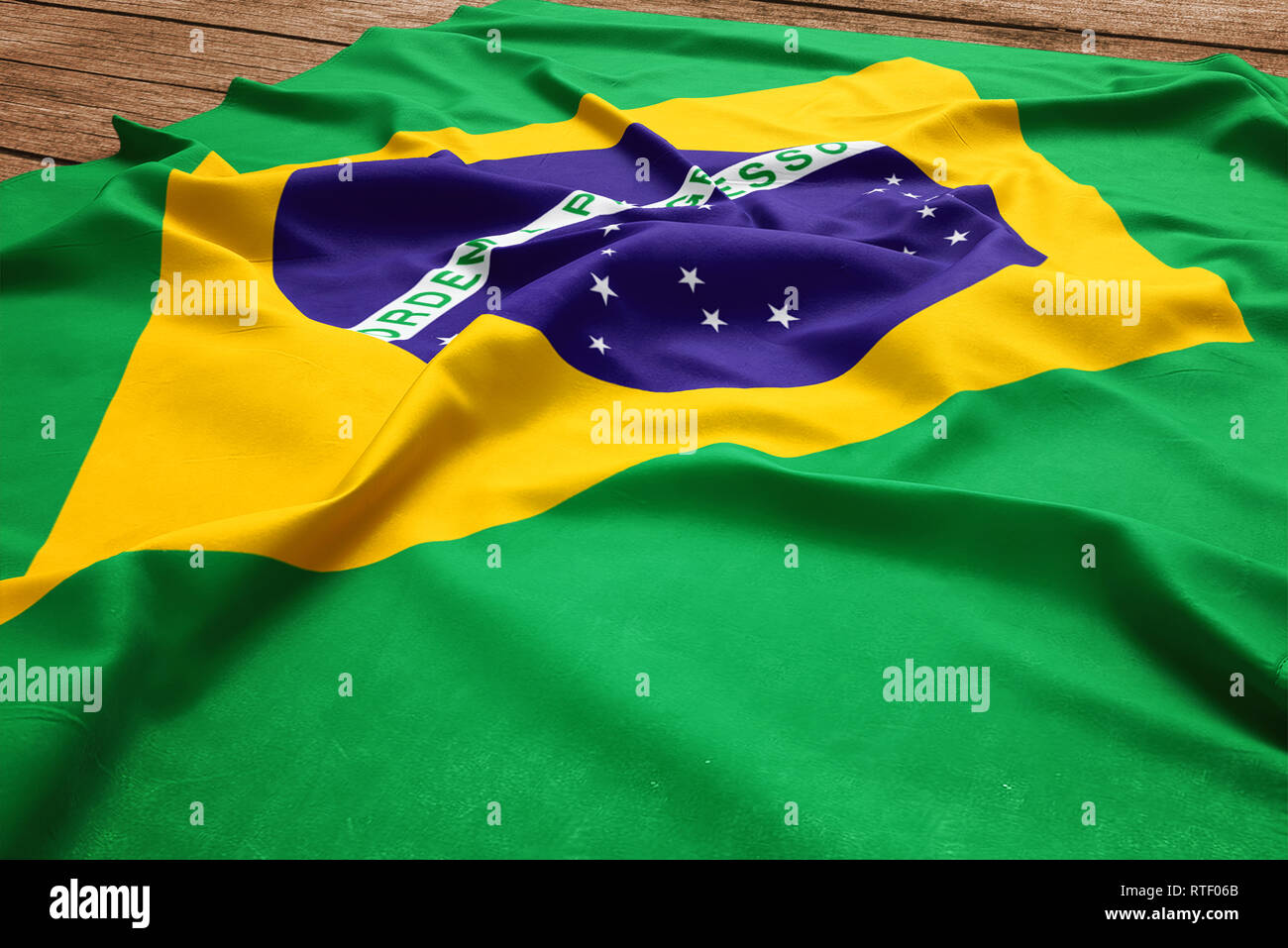 Flag of Brazil on a wooden desk background. Silk Brazilian flag top