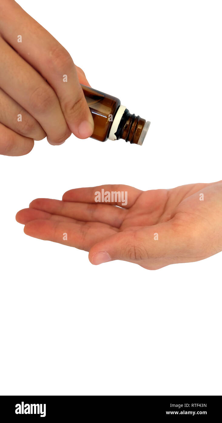 Hand holding a small glass bottle, dripping the liquid out onto another hand receiving it at the bottom. Stock Photo