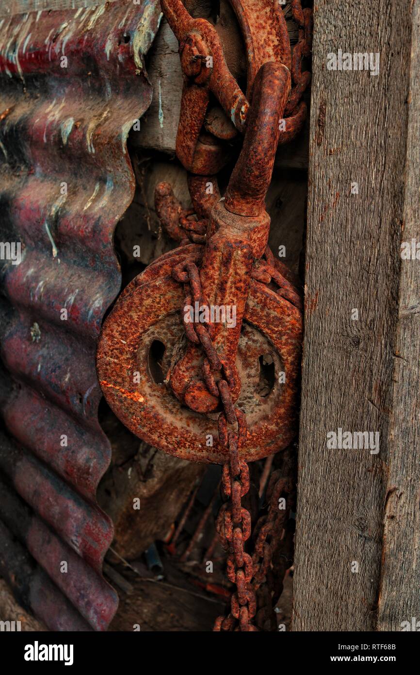 A rusty pulley and chain slowly decaying in the corner of a farmers barn. Stock Photo