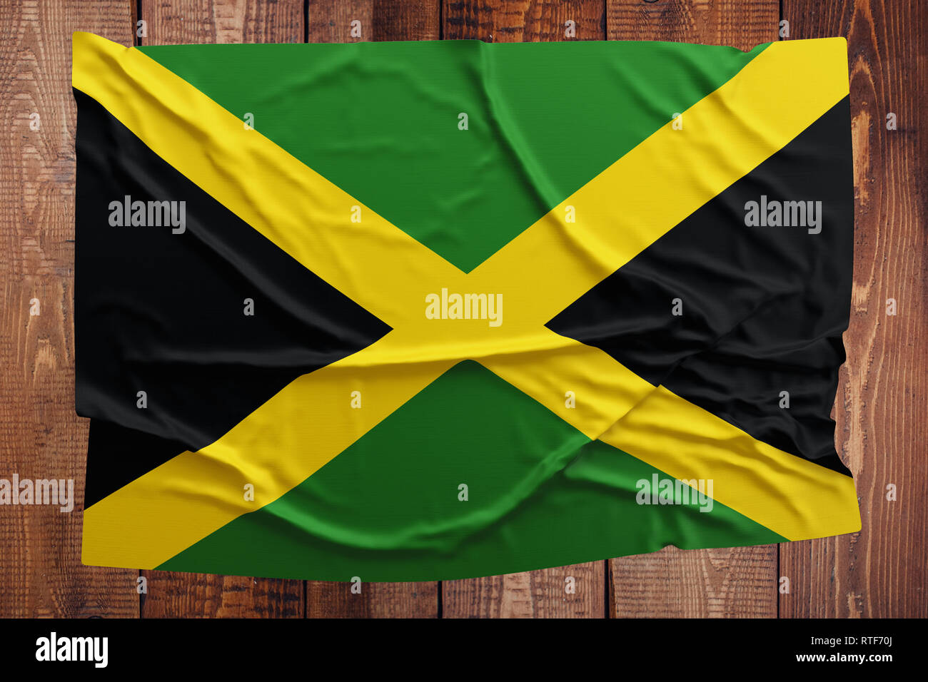 Flag of Jamaica on a wooden table background. Wrinkled Jamaican flag top view. Stock Photo