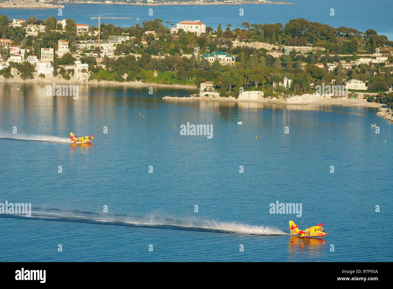 Two Canadair CL-415 refilling in the sheltered bay of Villefranche-sur-Mer to combat a nearby brushfire. French Riviera, France. Stock Photo