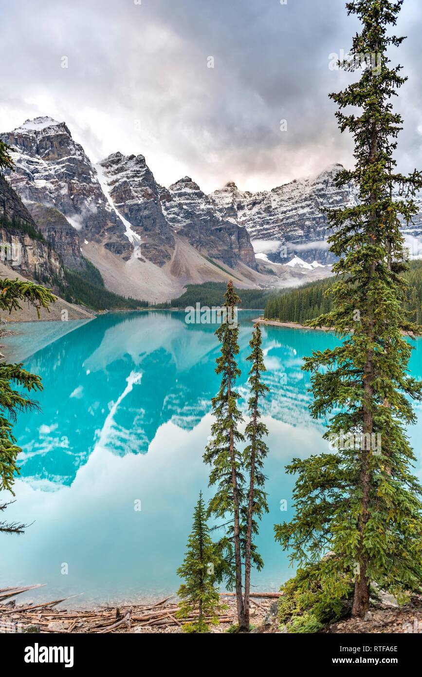Clouds hanging between mountain peaks, reflection in turquoise glacial lake, Moraine Lake, Valley of the Ten Peaks Stock Photo