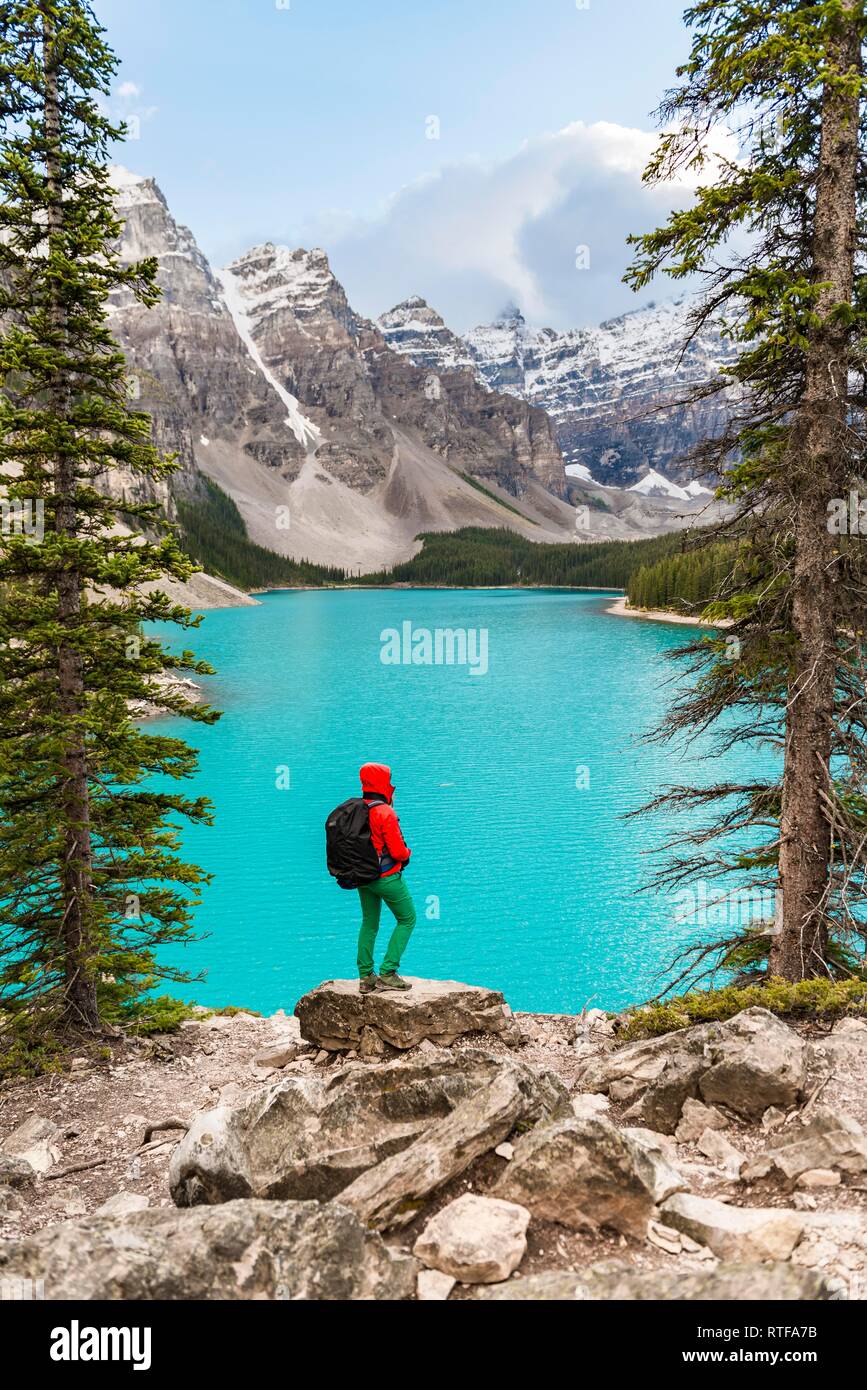 Hiker standing on the shore of a lake, mountain peaks at the back, turquoise glacial lake, Moraine Lake, Valley of the Ten Peaks Stock Photo