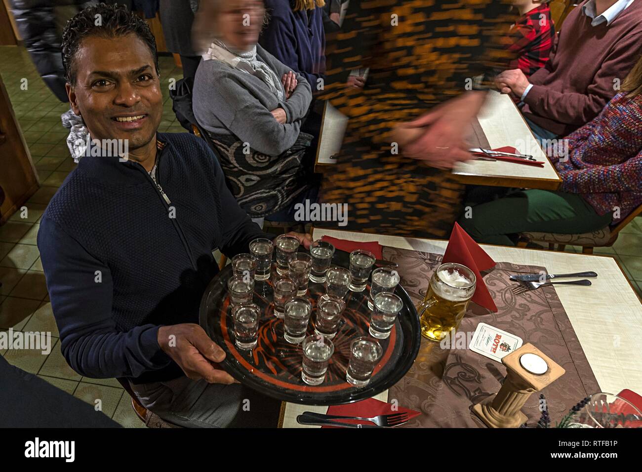 Waiter holds a tray of full Ouzoglasses in a restaurant, Bavaria, Germany Stock Photo