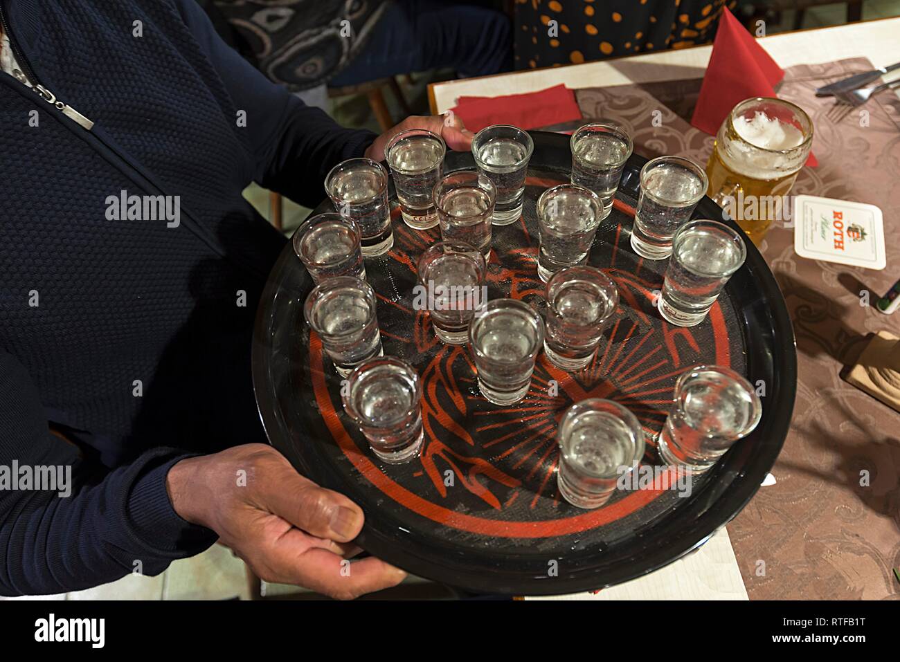 Waiter with tray of filled schnapps glasses in an inn, Lower Franconia, Bavaria, Germany Stock Photo