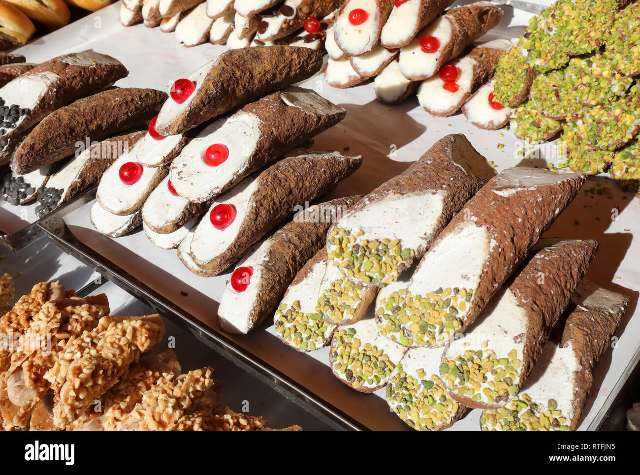 pastries with pistachio and cherry for sale in the pastry stand called Cannolo Siciliano in italian language Stock Photo