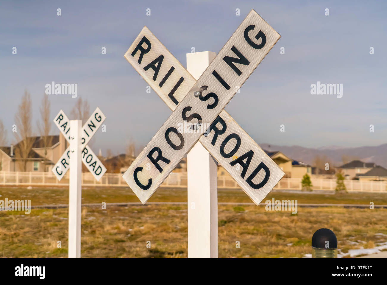 Railroad Crossing signs against homes and sky. Close up view of