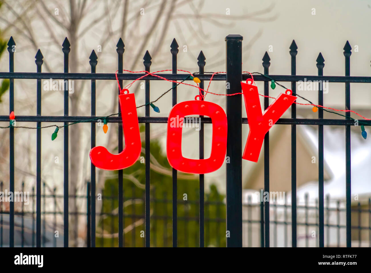 Red Joy and Christmas lights decoration on fence. Close up view of a