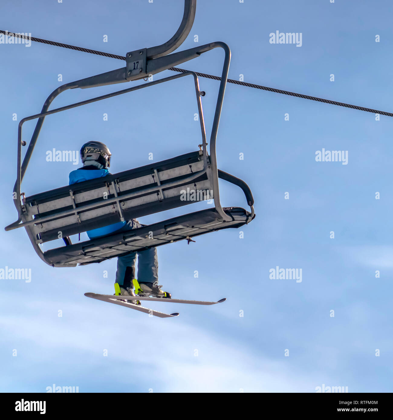 Skier on a chair lift against beautiful blue sky. Skier riding on a ...