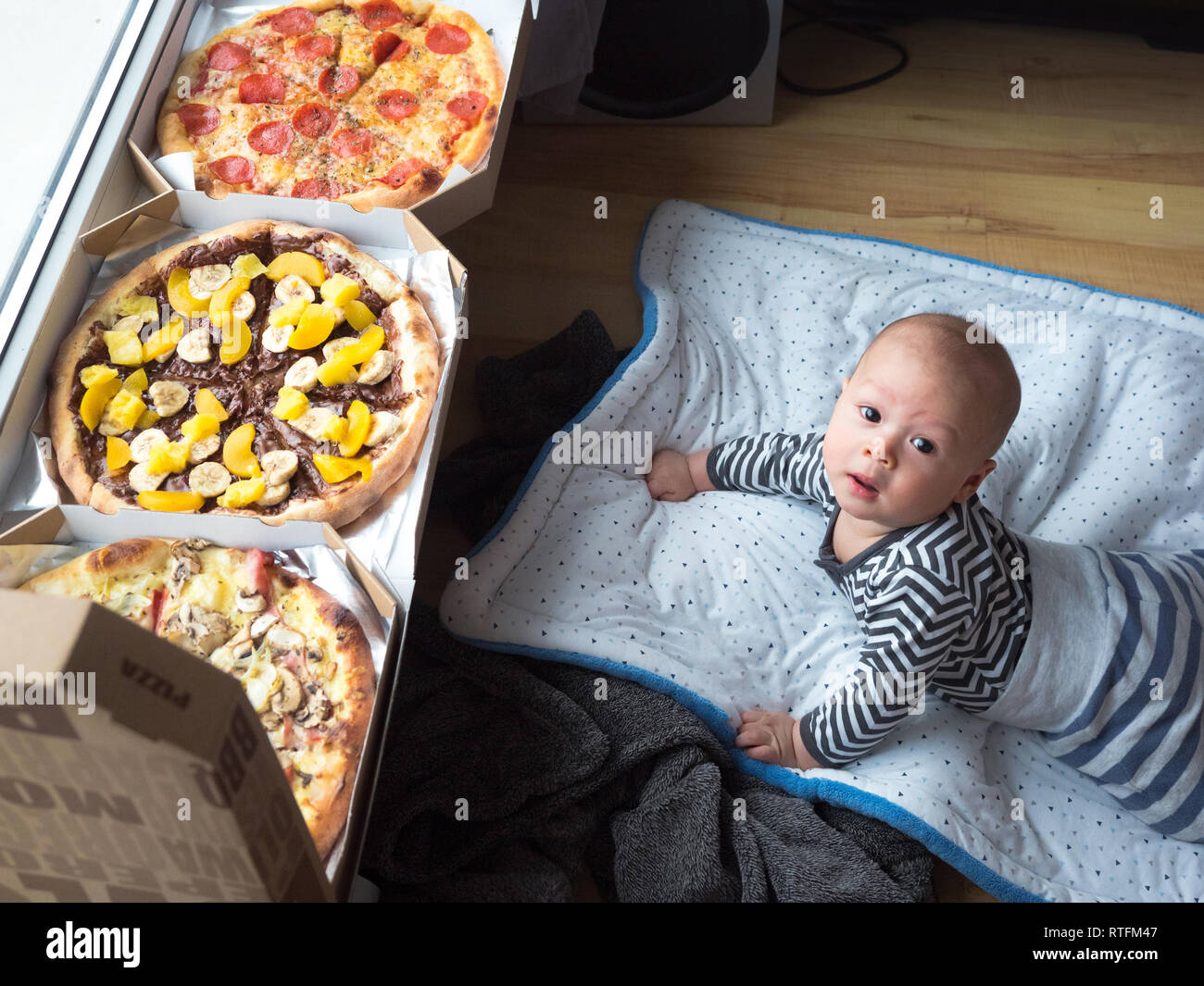 Mixed race baby mixed race Asian Caucasian boy next to big pizza delivery, very surprised by the size. surprised kid, baby boy Stock Photo