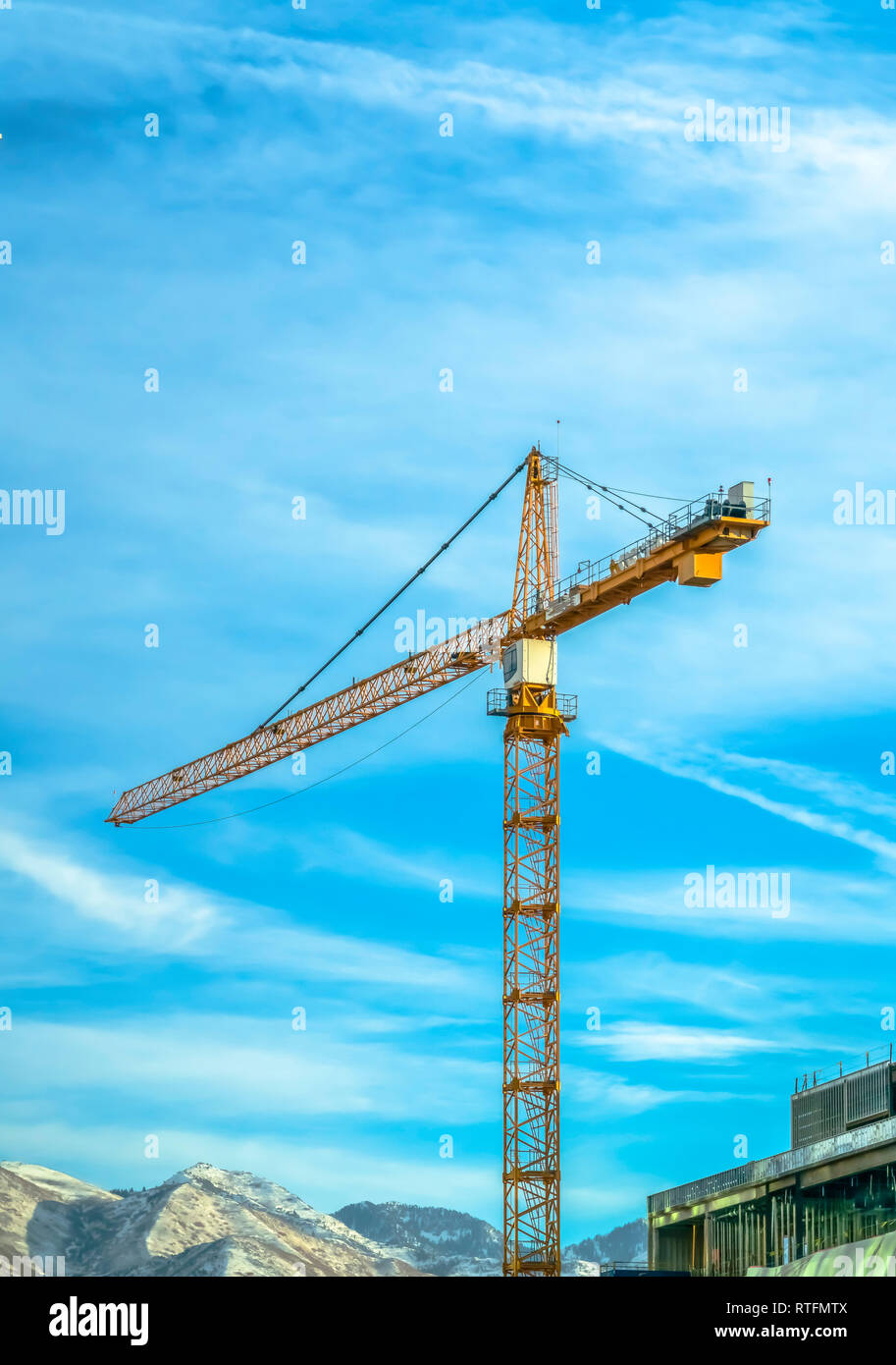 Tower crane and building against mountain and sky. View of a huge