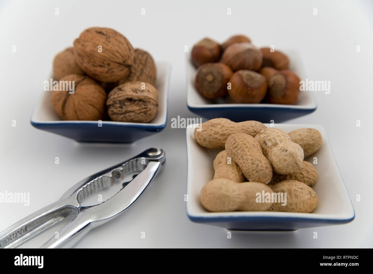 walnuts, hazelnuts and peanuts in three bowls on white background Stock Photo