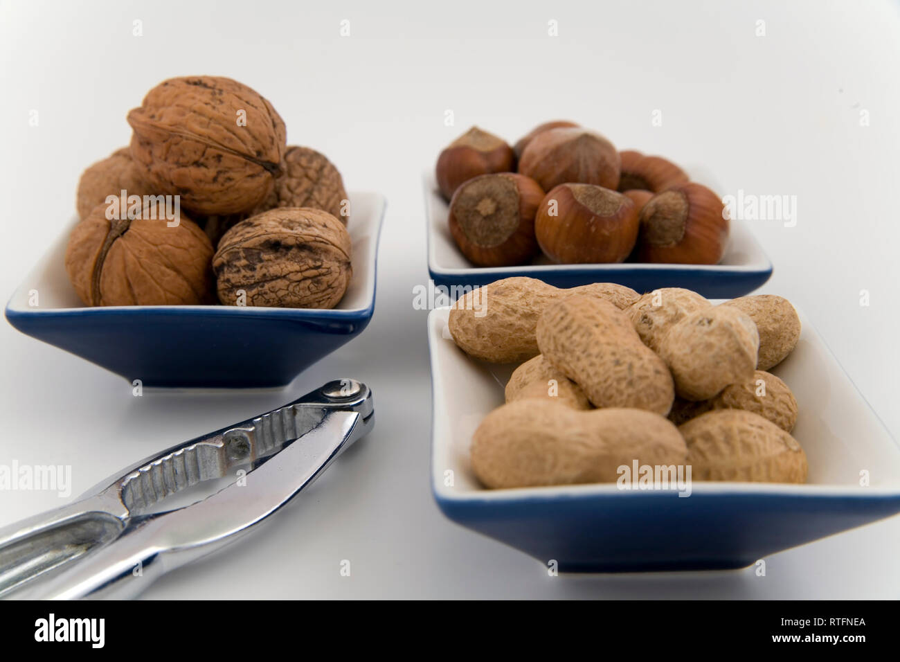 walnuts, hazelnuts and peanuts in three bowls on white background Stock Photo