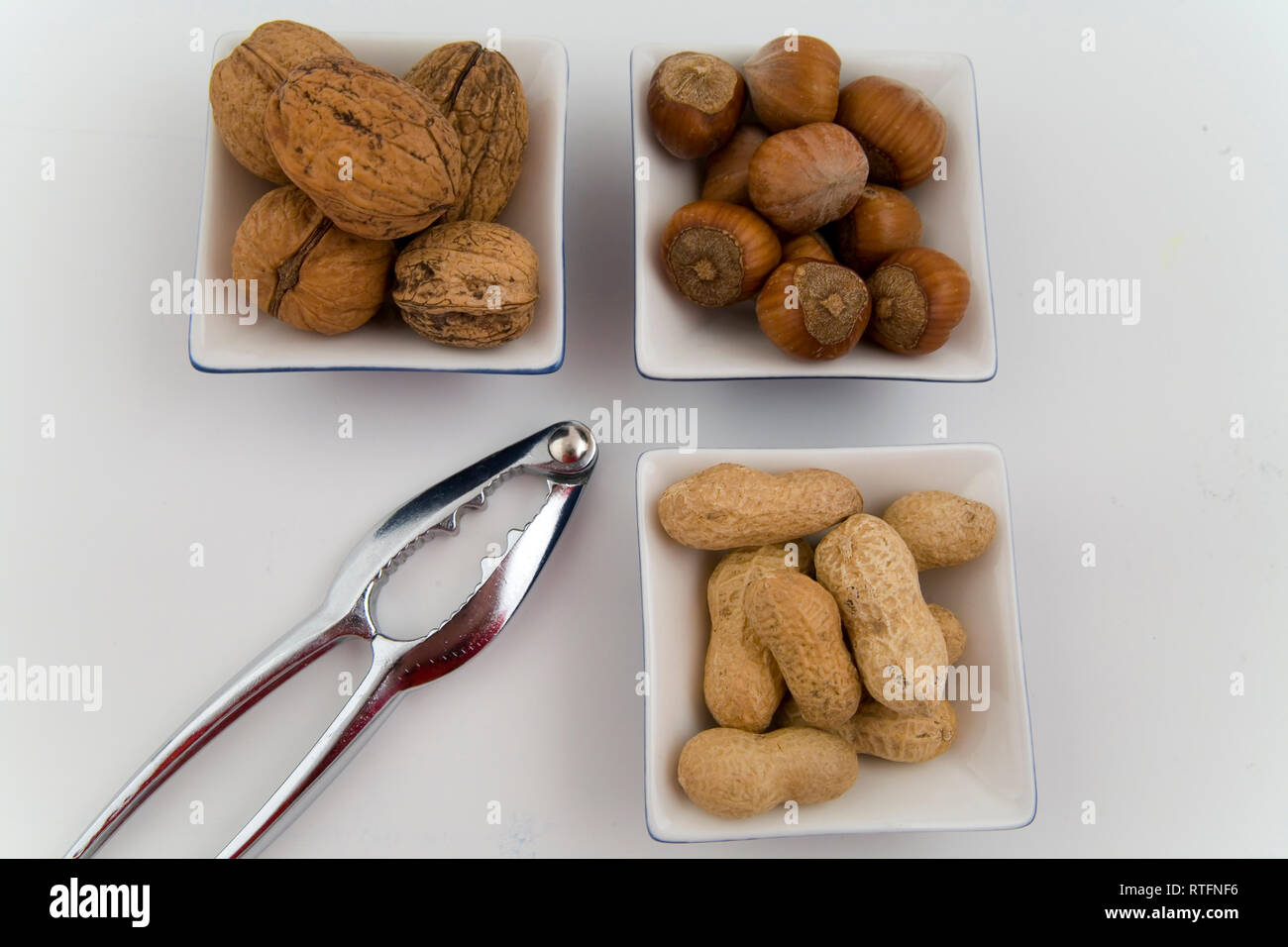 walnuts, hazelnuts and peanuts in three bowls on white background Stock Photo