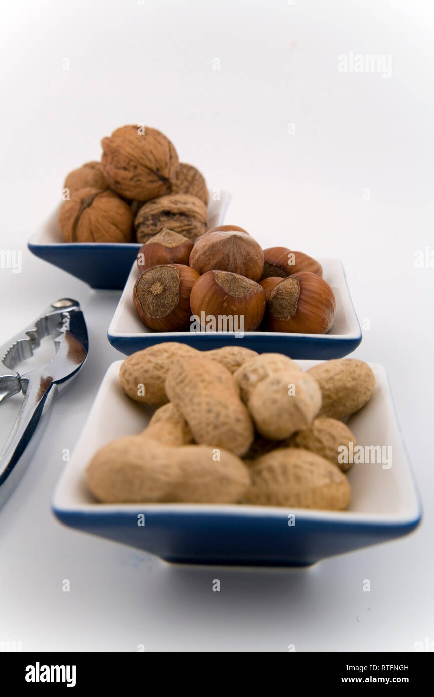 walnuts, hazelnuts and peanuts in three bowls on white background Stock Photo