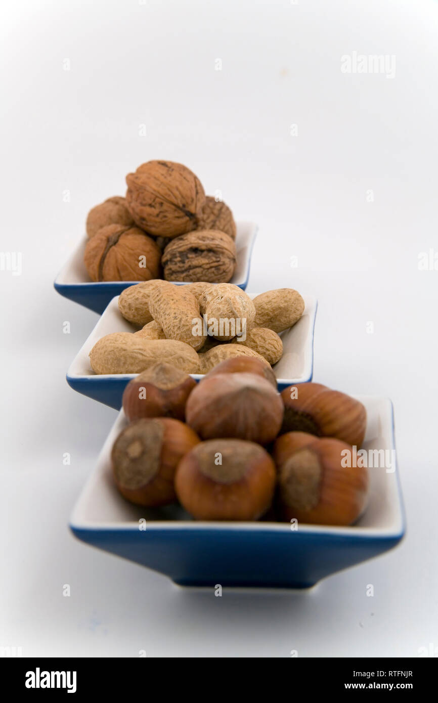 walnuts, hazelnuts and peanuts in three bowls on white background Stock Photo