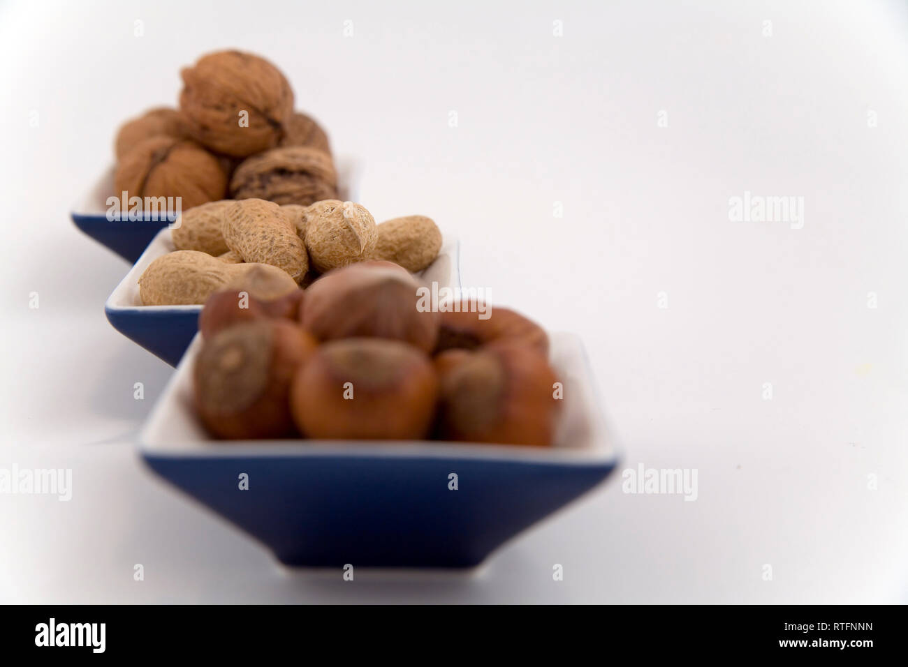 walnuts, hazelnuts and peanuts in three bowls on white background Stock Photo