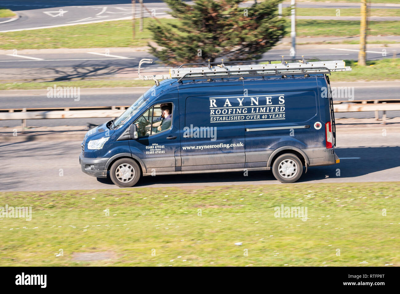 Raynes Roofing Limited commercial van driving on the road. Ladders on roof Stock Photo