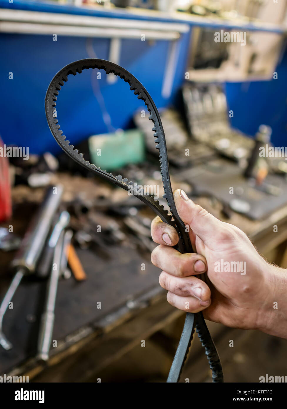 Old worn rubber alternator belt in men's hands. The concept of car