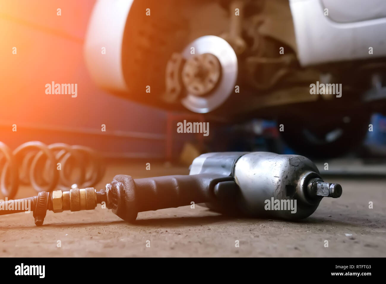 Auto mechanic man with electric screwdriver changing tire outside. Car