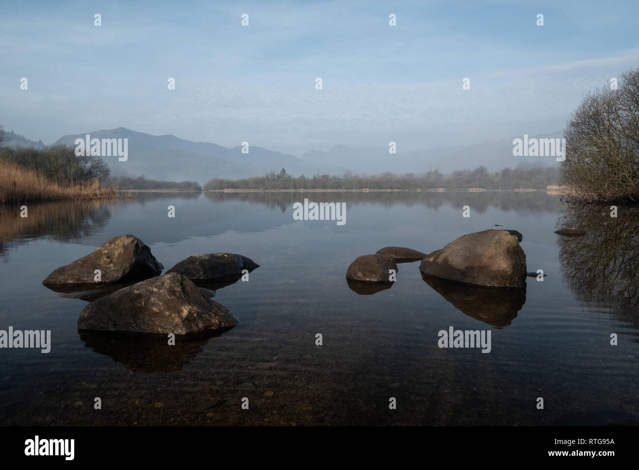 The Langdale Pikes and Lingmoor Fell seen over the rocky foreshore of Elter Water, Lake District, UK Stock Photo