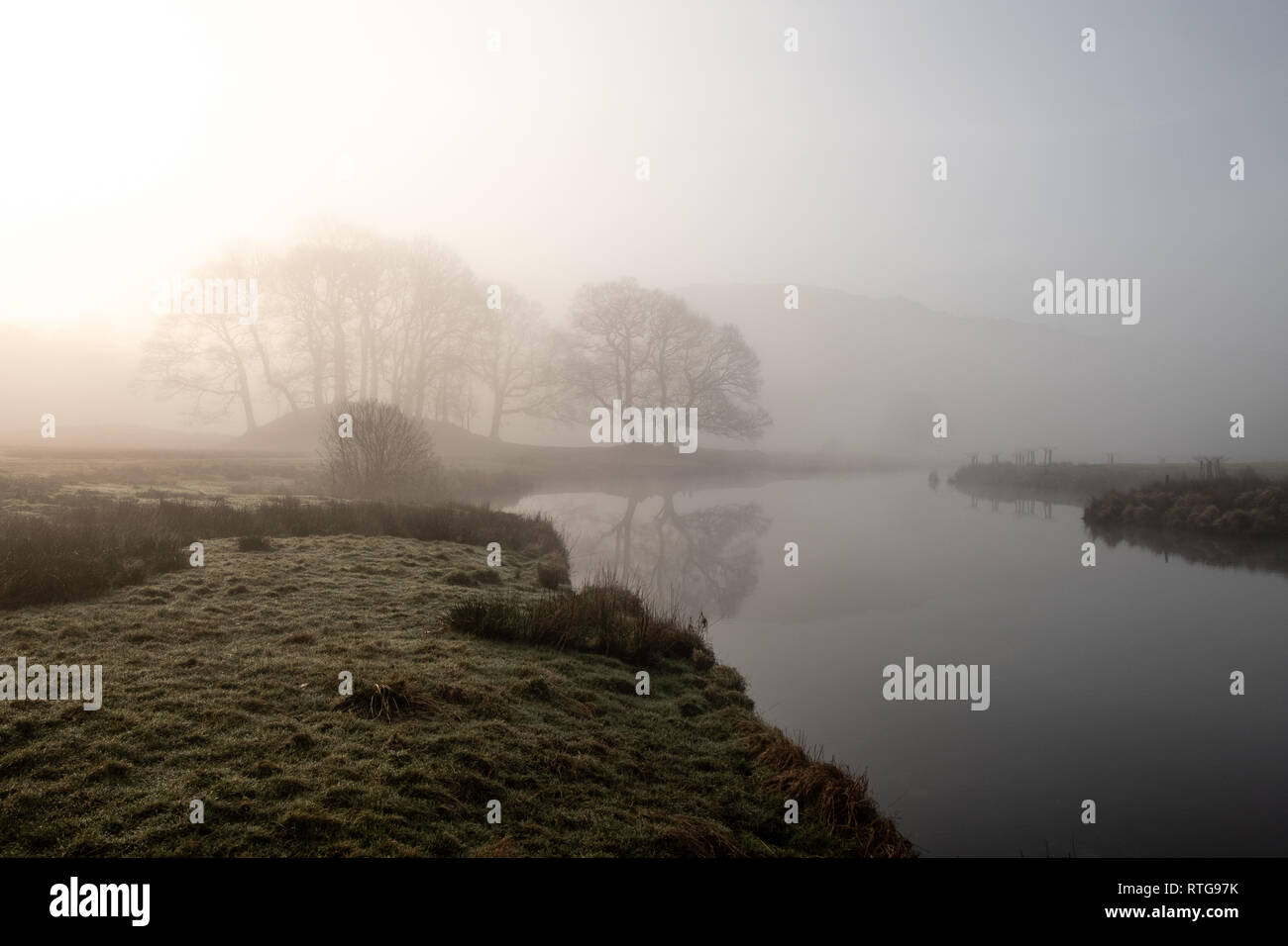 Early morning mist hanging over the River Brathay between Elterwater and Skelwith Bridge. Two people seen in the distance. Lake District, UK Stock Photo