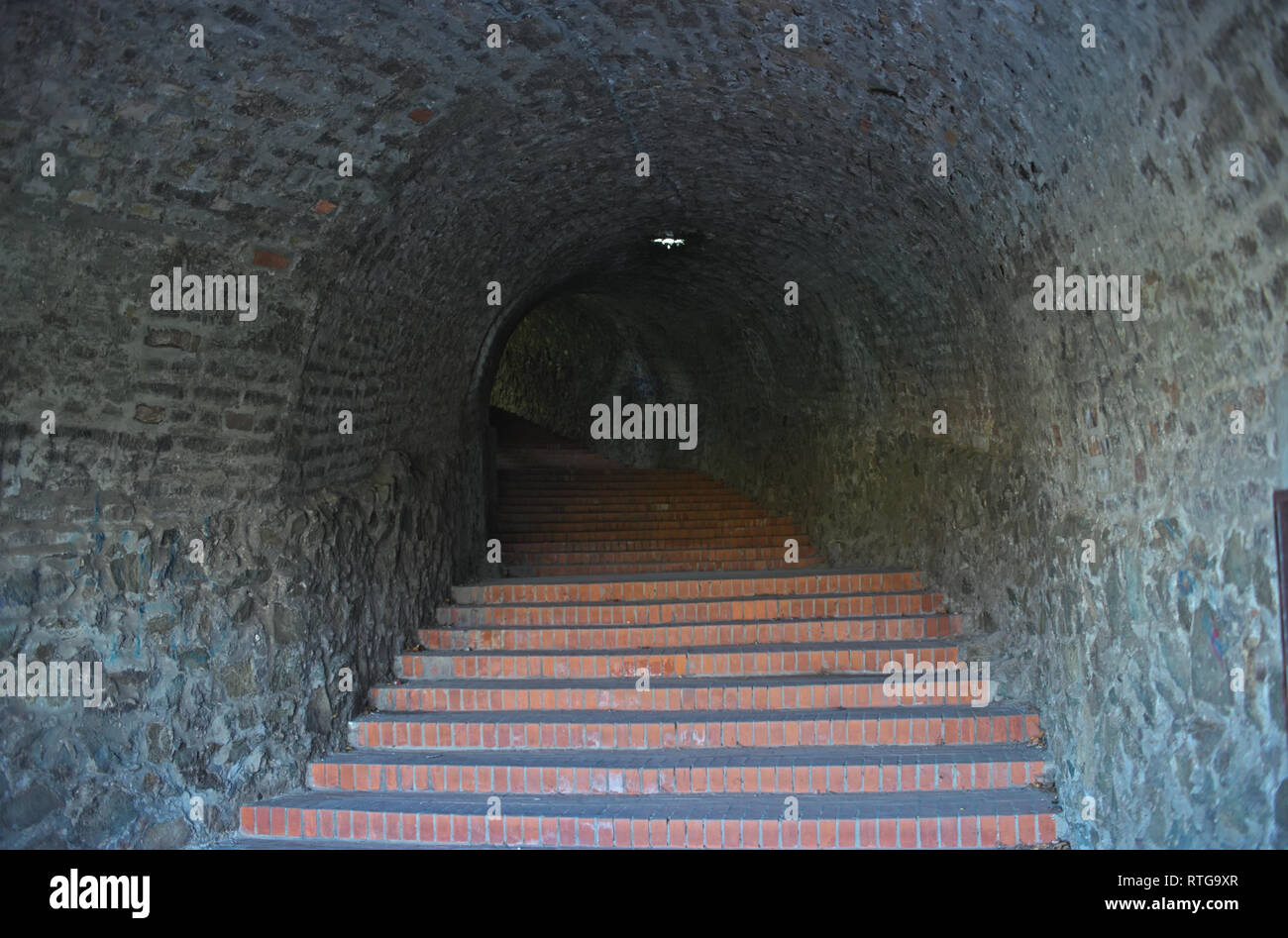 Long dark tunnel with red bricks stairs going up Stock Photo
