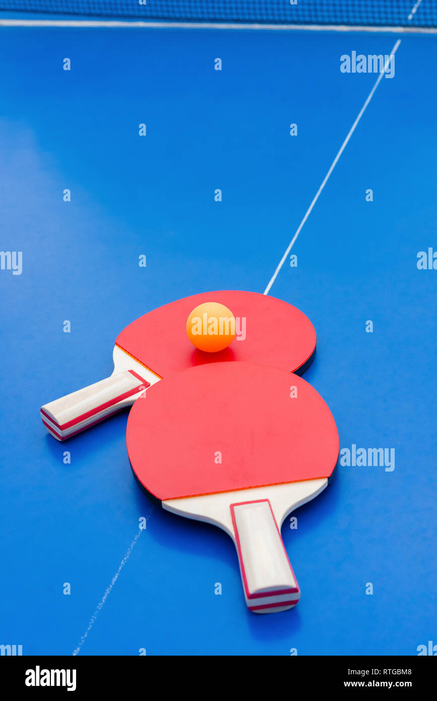 pingpong rackets and ball and net on a blue pingpong table Stock Photo