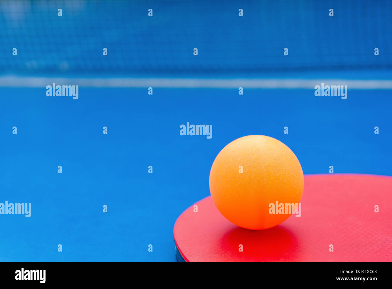 pingpong racket and ball and net on a blue pingpong table Stock Photo