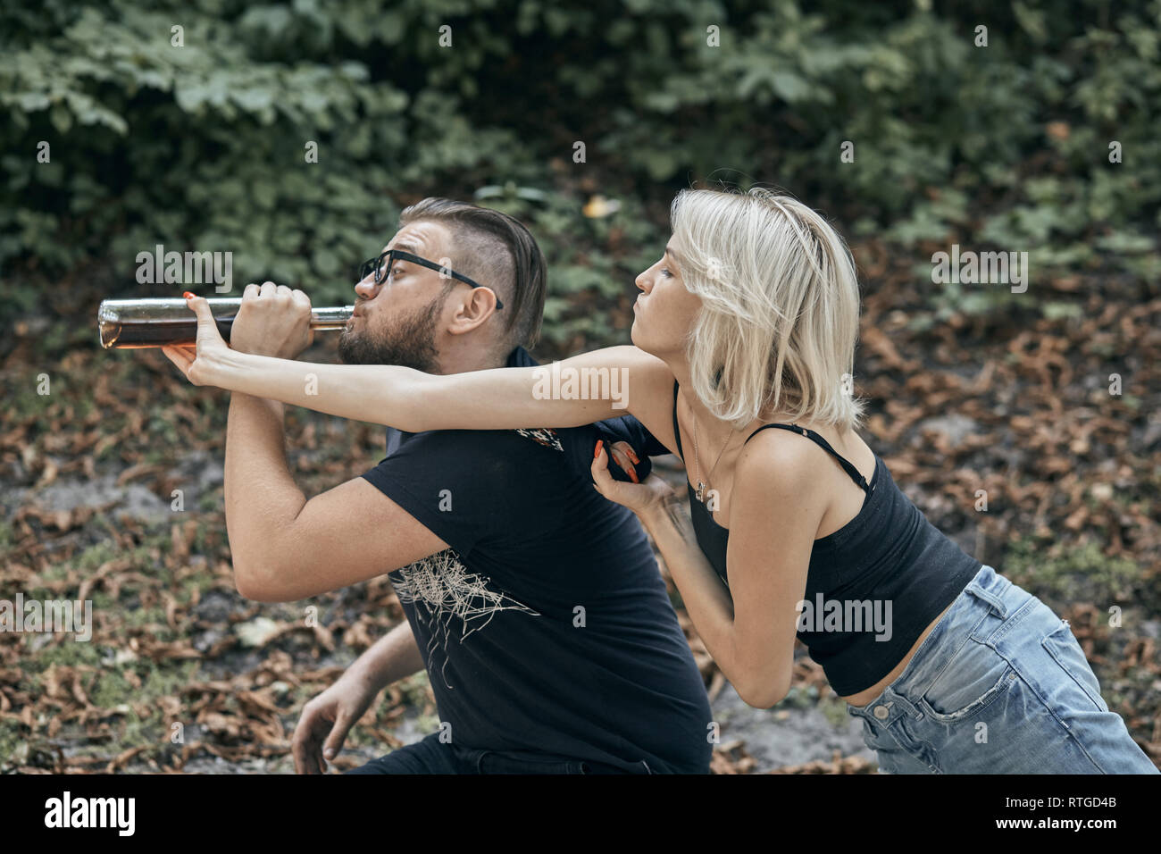 Couple sitting on the table and drinking alcohol. Drunk young people (alcoholism in family, pain, pity, hopelessness, social problem of dependence, de Stock Photo