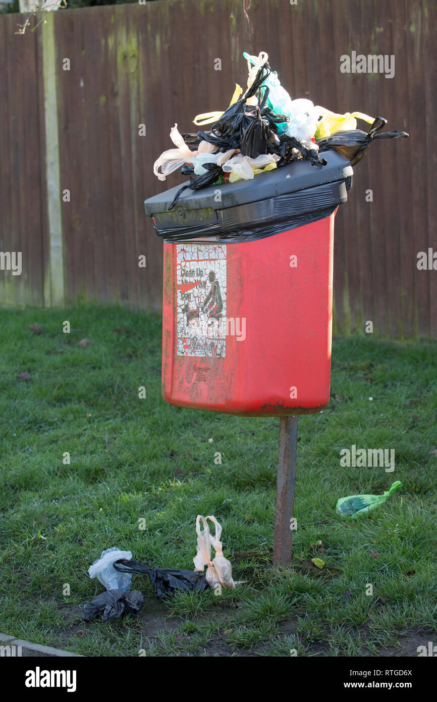An overflowing bin of poo bags containing dog dirt in a suburban street. North Dorset England UK GB Stock Photo
