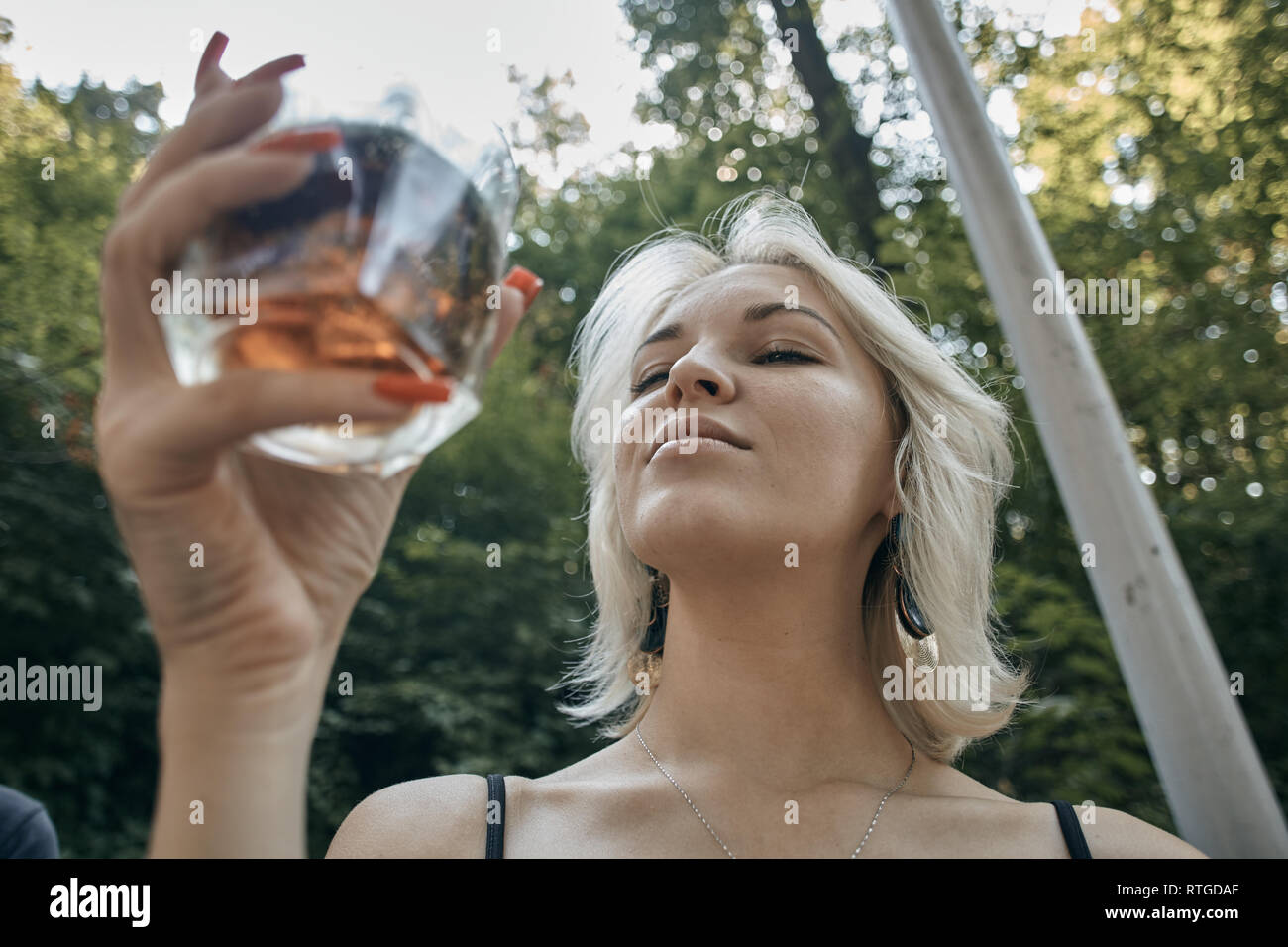 Young female with alcoholic drink looking very sad and depressed. Drunk young people (alcoholism, pain, pity, hopelessness, social problem of dependen Stock Photo