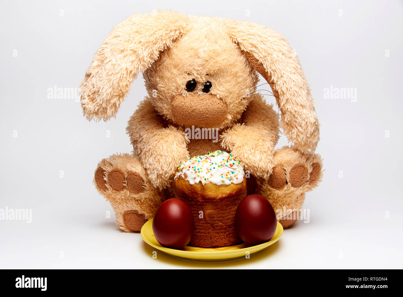 Stuffed soft rabbit with Easter cake and painted eggs on a white background. Stock Photo