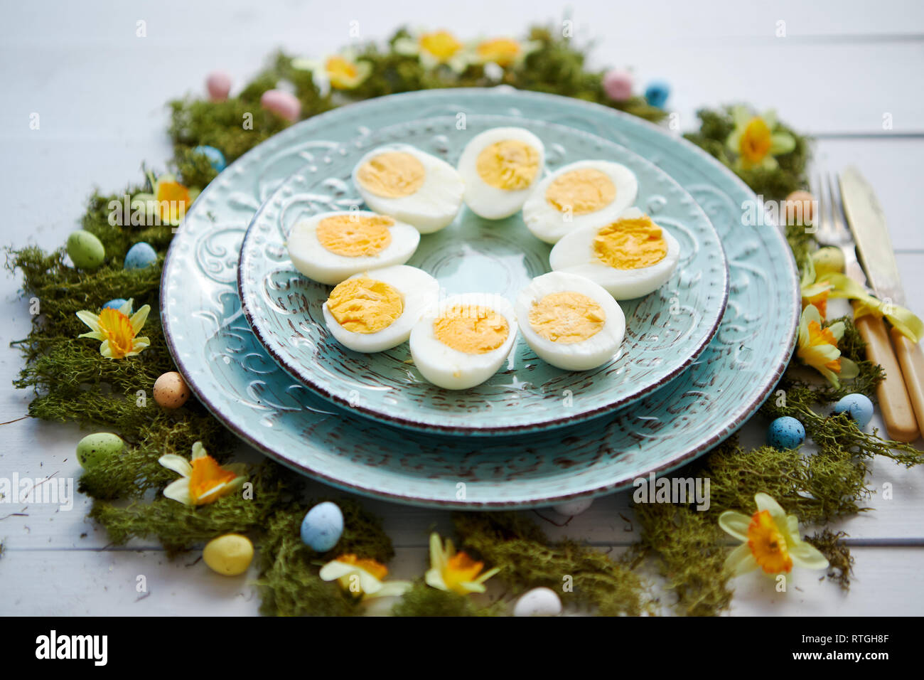 Easter table setting with flowers and eggs. Decorative plates with boiled eggs Stock Photo