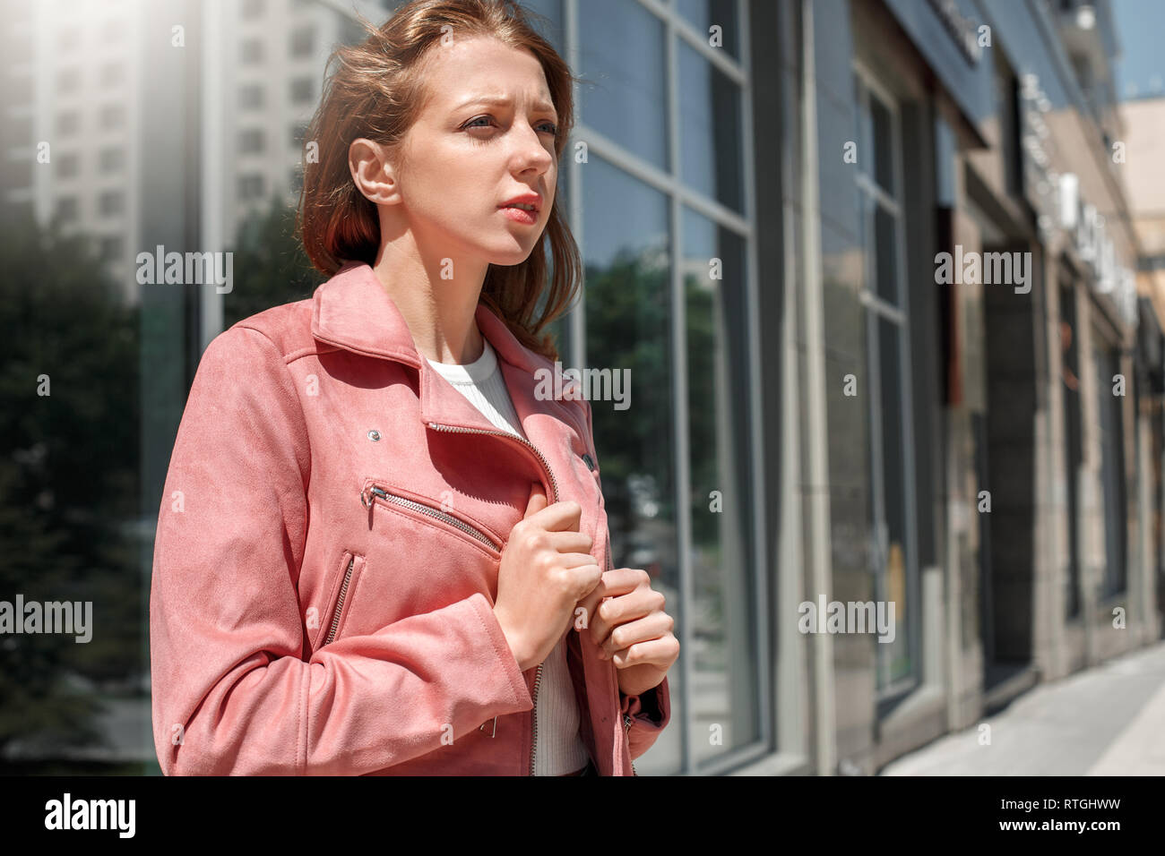 Young girl wearing jacket standing on the city street looking forward