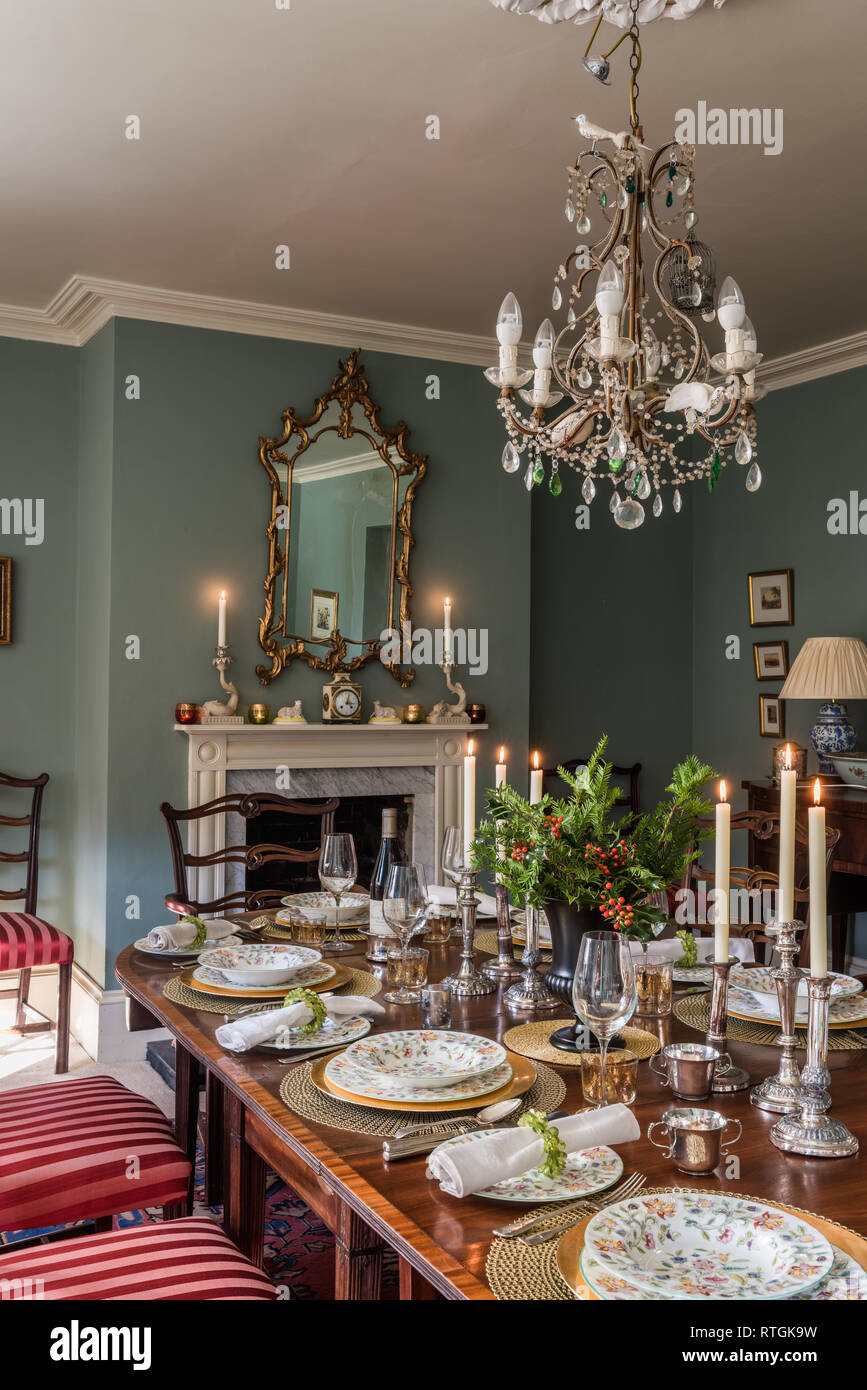 Mahogany dining table with chairs upholstered in Regency stripe with English fireplace Stock Photo