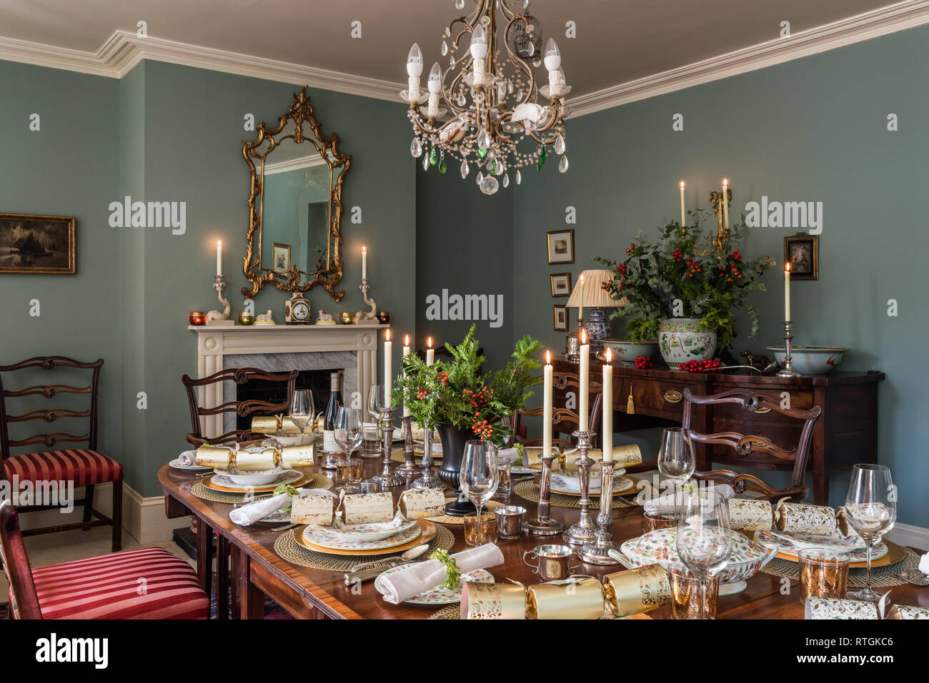 Mahogany dining table and Georgian sideboard with chairs upholstered in Regency stripe with English fireplace Stock Photo