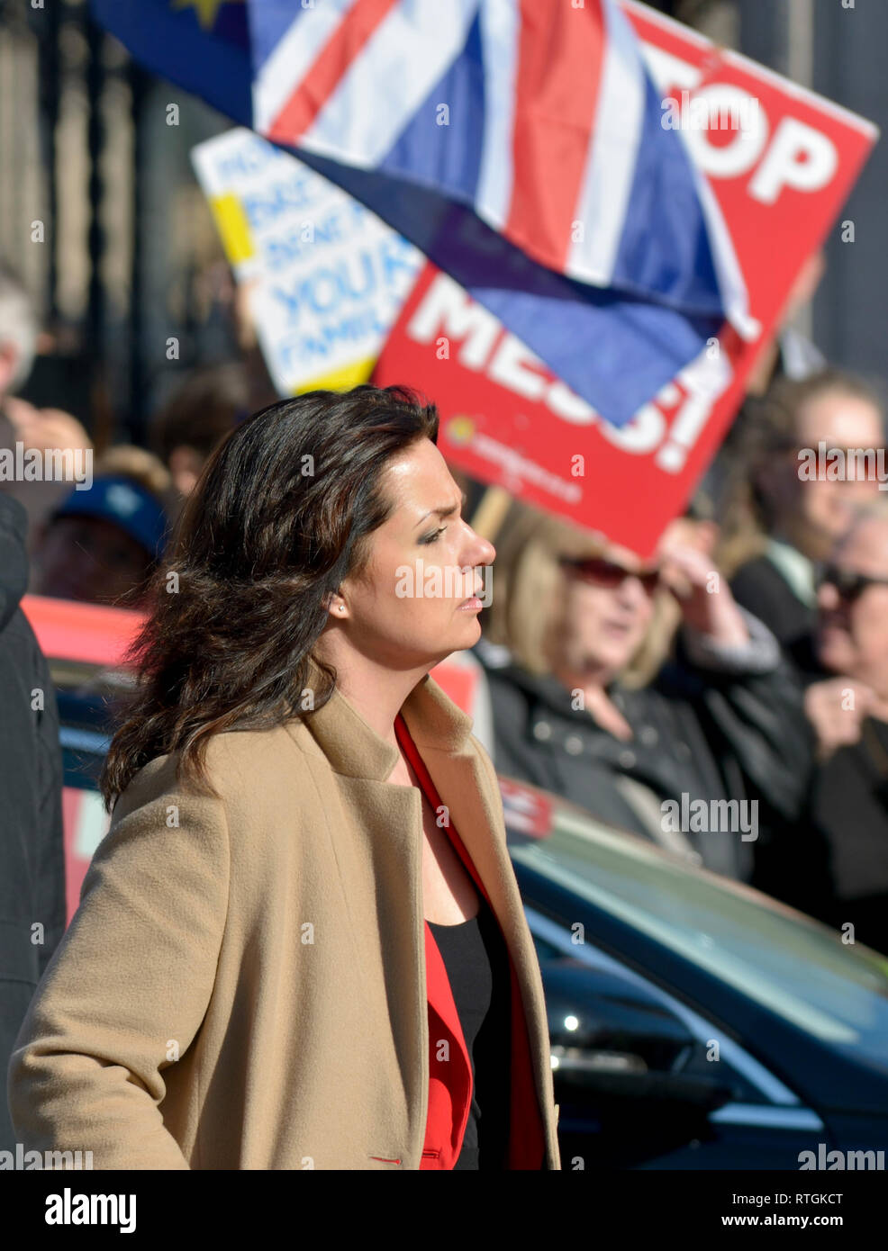 Heidi Allen MP (Independent Group, Con: South Cambridgeshire) walking quickly past rival pro- and anti-Brexit protests at the gates of the Houses of P Stock Photo