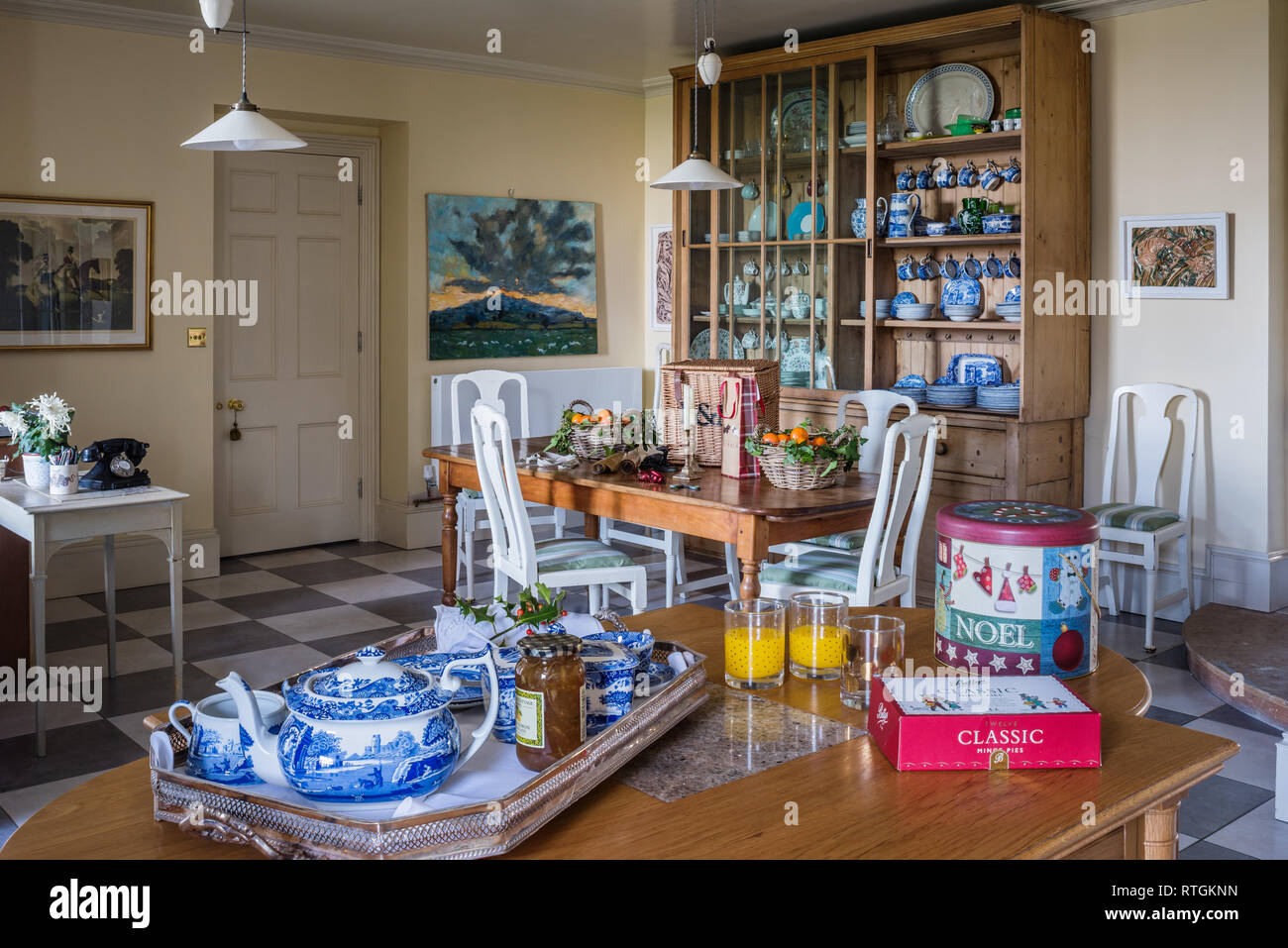 Breakfast tray with pine, glass fronted kitchen dresser and table with white painted chairs Stock Photo