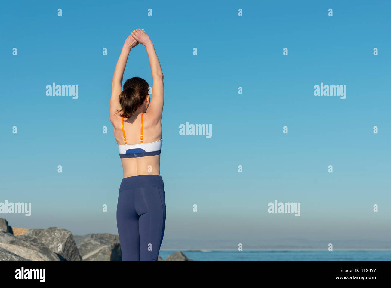 back view of a woman doing an arm stretch outdoors, morning warm up exercises Stock Photo